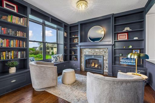 Cozy up by the stunning stone fireplace surrounded by custom built-ins and rich millwork. This beautifully designed library/hearth room offers the perfect retreat for reading, relaxing, or working from home. Enjoy year-round views to Lake Waconia.