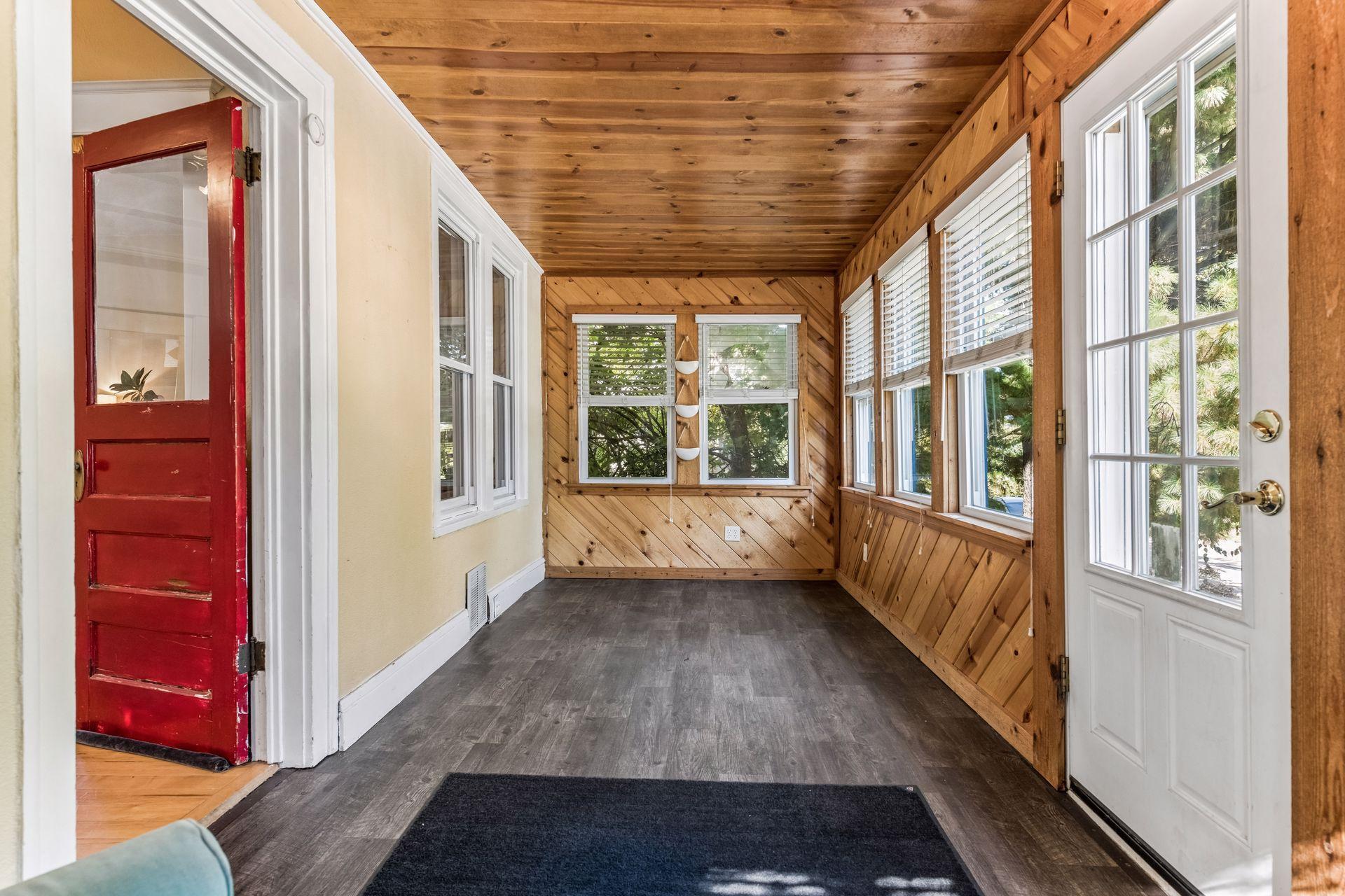 Another view of the inviting front porch highlights the beautiful natural wood finishes and windows on multiple sides. A versatile space with room for comfortable seating or a cozy reading nook.