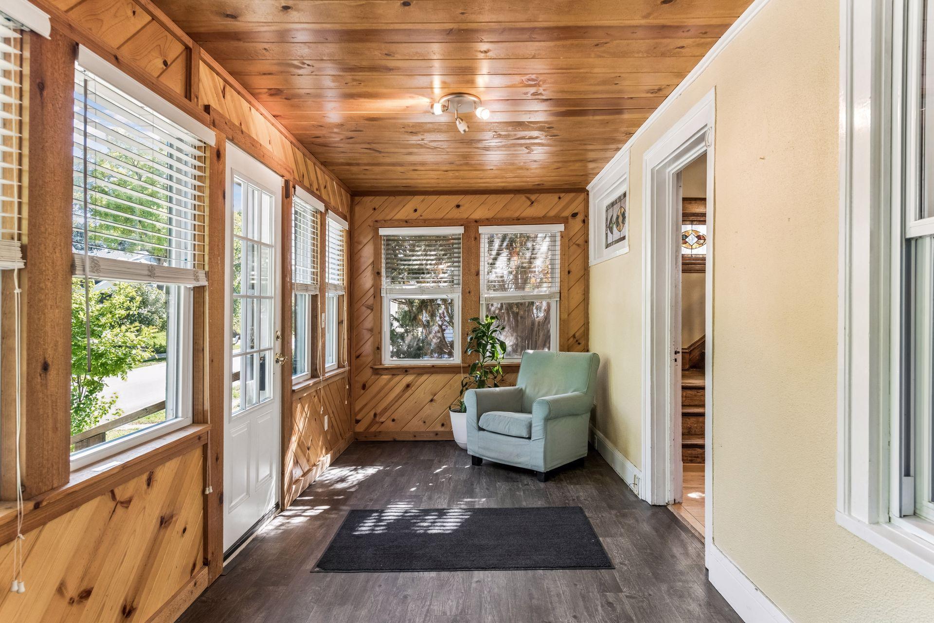 The enclosed front porch welcomes you with warm wood-paneled walls and ceiling, a wonderful collection of windows, and plenty of natural light. A charming space to relax and enjoy the neighborhood views.