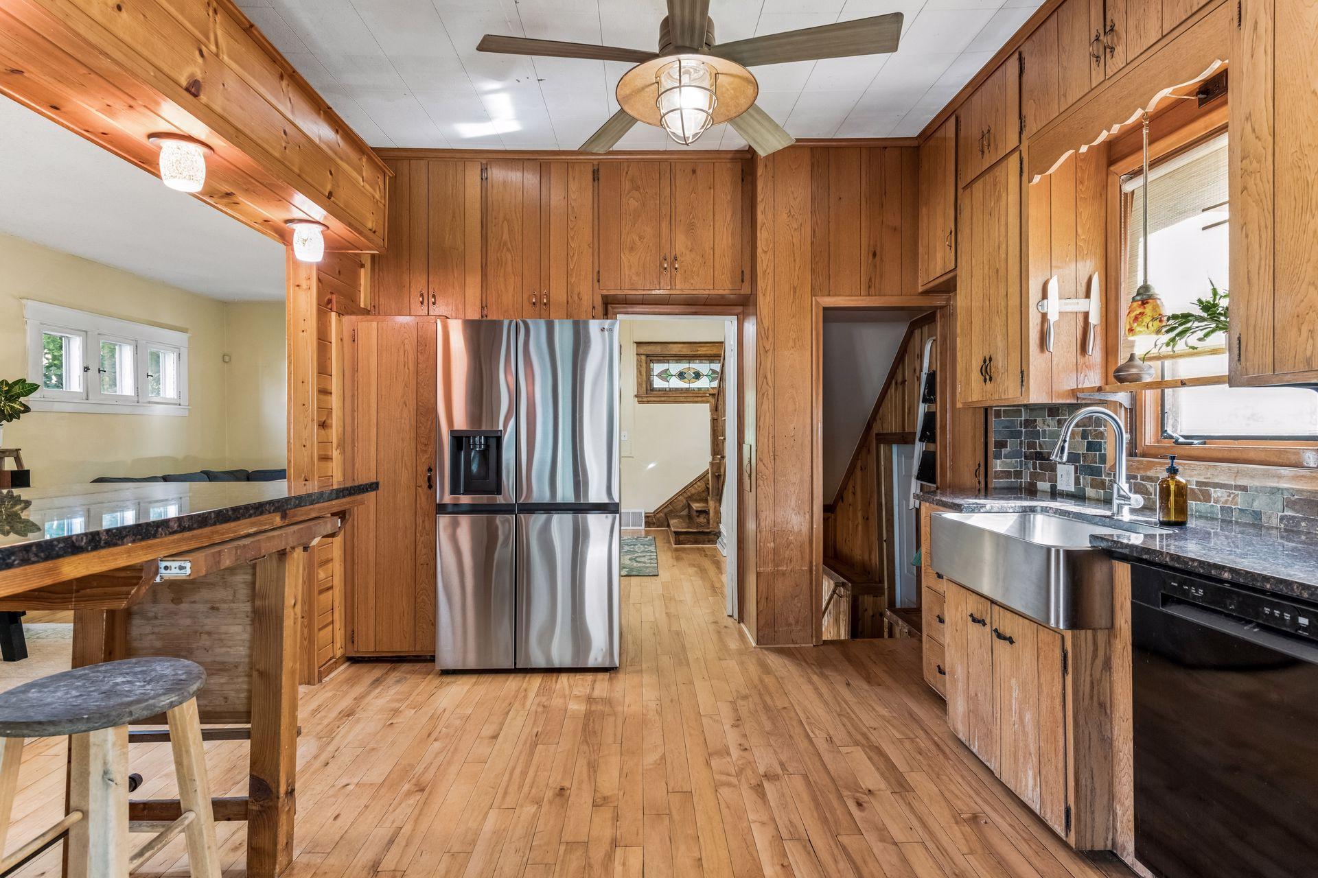 A wonderful combination of finishes featuring rich wood cabinetry, attractive tile backsplash, updated countertops, and a farmhouse-style stainless steel sink.