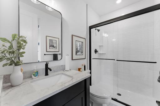 This bathroom is easily accessible from the main living area and bedroom 5, complete with a single vanity and glass-enclosed shower.
