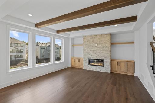 This sun-drenched family room features a charming fireplace at its center, inviting residents to gather around on the couch, host movies nights and enjoy the company of loved ones.