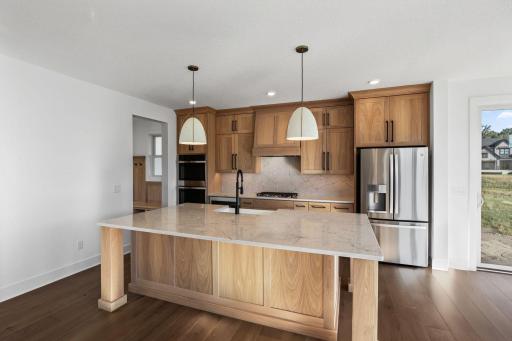 A home chefâs dream, this upscale kitchen showcases a quartz-topped center island with elegant pendant lights at the focal point.