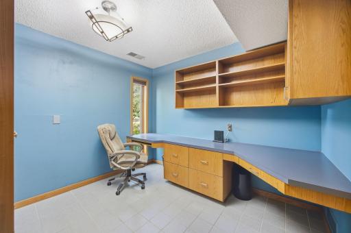 33- Office with built in desk with shelving and cabinetry. Tile floor.