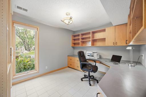 34- Office with tile floor and large windows with built in desk and shelving.