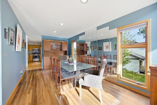 Light-filled dining room with hardwood flooring and a striking mirrored accent wall