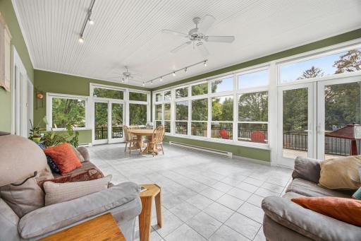 Year-round sunroom featuring tile flooring, abundant natural light, and access to the wraparound deck.