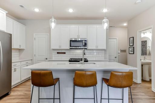 Large center island with quartz countertops and seating for three.