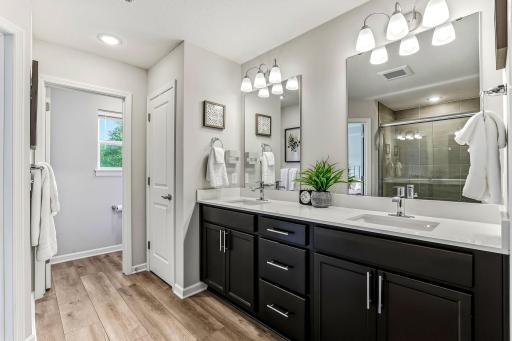 Another view of the primary en-suite with double sinks, quartz countertop, and walk-in shower.