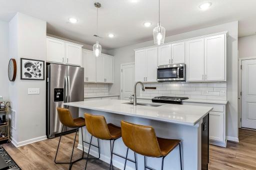 The kitchen features quartz countertops, a large center island with seating, a walk-in pantry, soft-close drawers, and pull-out lower cabinets.