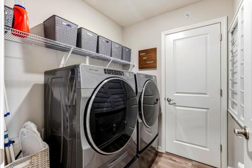 Convenient upper-level laundry room with extra shelving, storage space, and a unique drying rack.