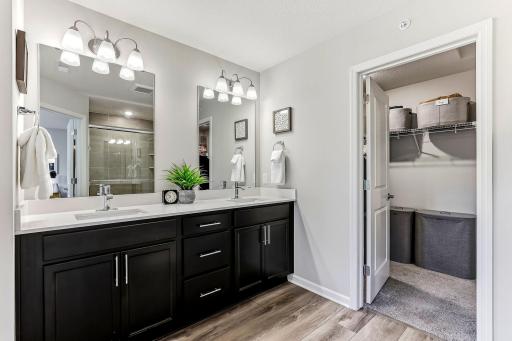 Primary en-suite 3/4 bath with double sinks, quartz countertop, walk-in shower, and walk-in closet.