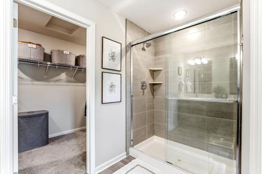 Primary bath features a tiled walk-in shower with glass doors and convenient access to the walk-in closet.