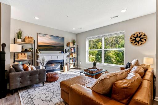 Bright, inviting living room with large windows overlooking a peaceful, wooded setting. Freestanding fireplace is negotiable. Framed TV excluded.
