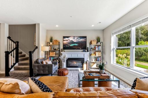 Spacious living room with large windows, great natural light, and a cozy fireplace. The framed TV is not included in the sale.