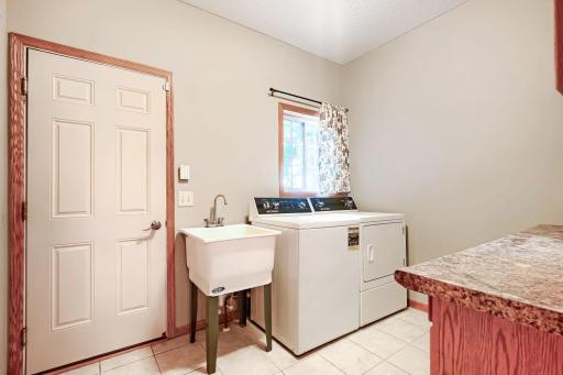 Entrance from the garage, including this large laundry area with built-in cabinets and ceramic floor.