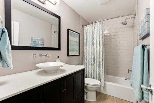 Updated second full bath featuring a modern vessel sink, spacious vanity, and tiled tub/shower surround.