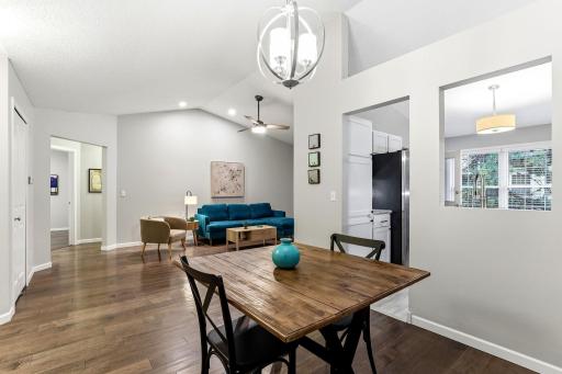 Open dining area with vaulted ceilings and wood flooring, offering seamless flow to the living room and kitchen.
