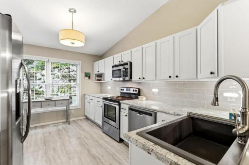 Bright kitchen with abundant cabinetry, stainless steel appliances, generous counter space, and a large window that brings in plenty of natural light.
