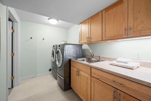 Large laundry room with nice appliances, counter top and wash tub and storage