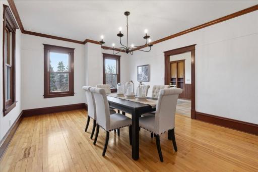 Elegant formal dining room features hardwood floors, detailed wood trim, beautiful natural light and classic chandelier.