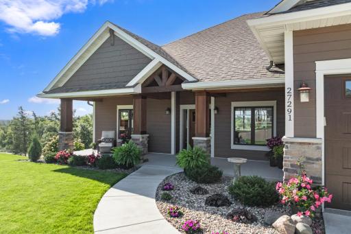 Welcoming covered front porch showcases beautiful timber accents, stone columns, professional landscaping, and a gracious entry into this executive rambler.