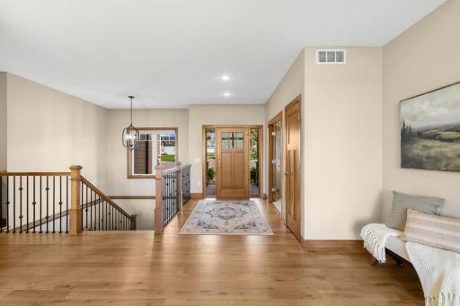 Looking back toward the entry, the open main level showcases beautiful hardwood floors, warm woodwork, and stylish iron railings.