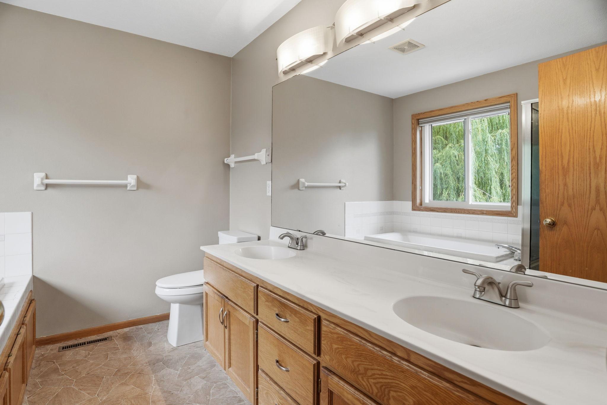 Double vanity sinks are the buyer favorite, stretching beneath a full wall mirror in this primary ensuite while a soaking tub waits at the far end.