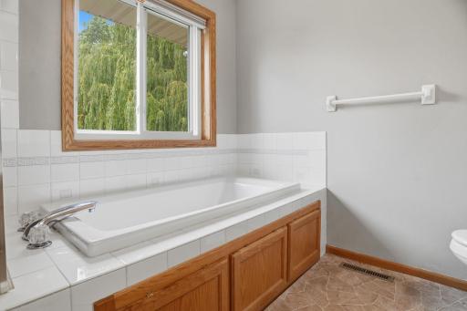 Soak away the day here. This deep primary suite tub sits beneath a window framed in willow branches, a private tiled alcove built for relaxing.
