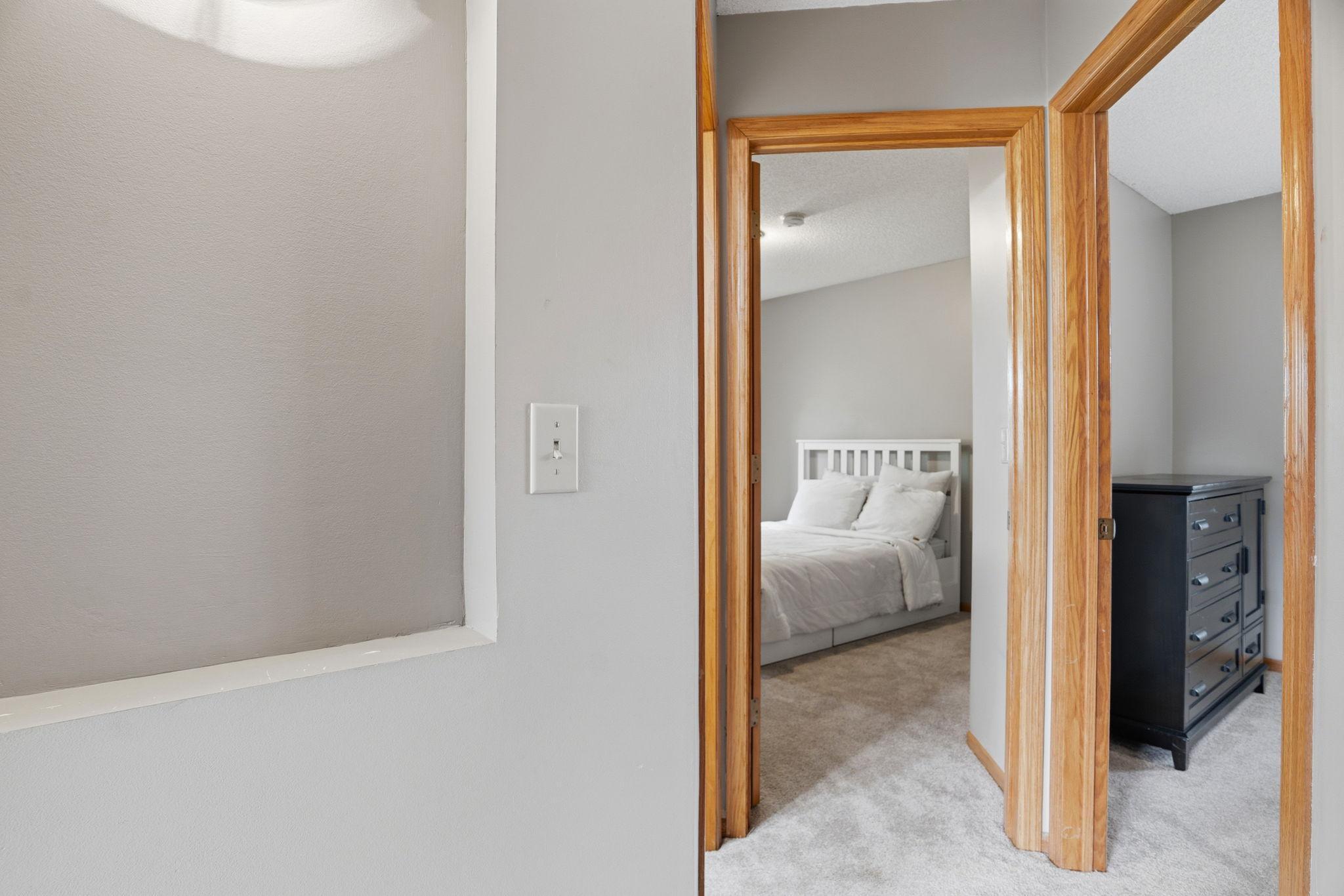 Oak framed doorways connect this upper hallway to bedrooms on either side, plush carpet carrying that same warm, custom feel throughout the upper level.