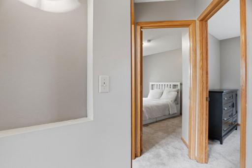 Oak framed doorways connect this upper hallway to bedrooms on either side, plush carpet carrying that same warm, custom feel throughout the upper level.
