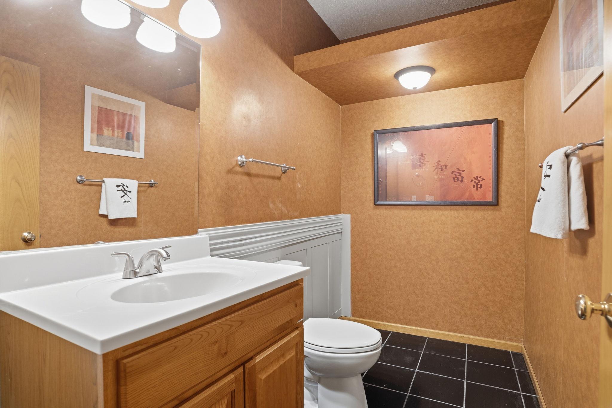 A convenient powder room finishes off the lower level, wainscoting and tile flooring adding a custom touch beneath an angled ceiling.