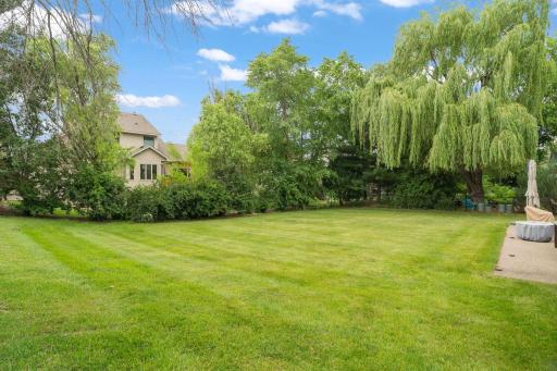This is the backyard buyers picture in their dreams. A sweeping lawn stretches beneath a weeping willow toward a stone patio built for evenings by the fire.