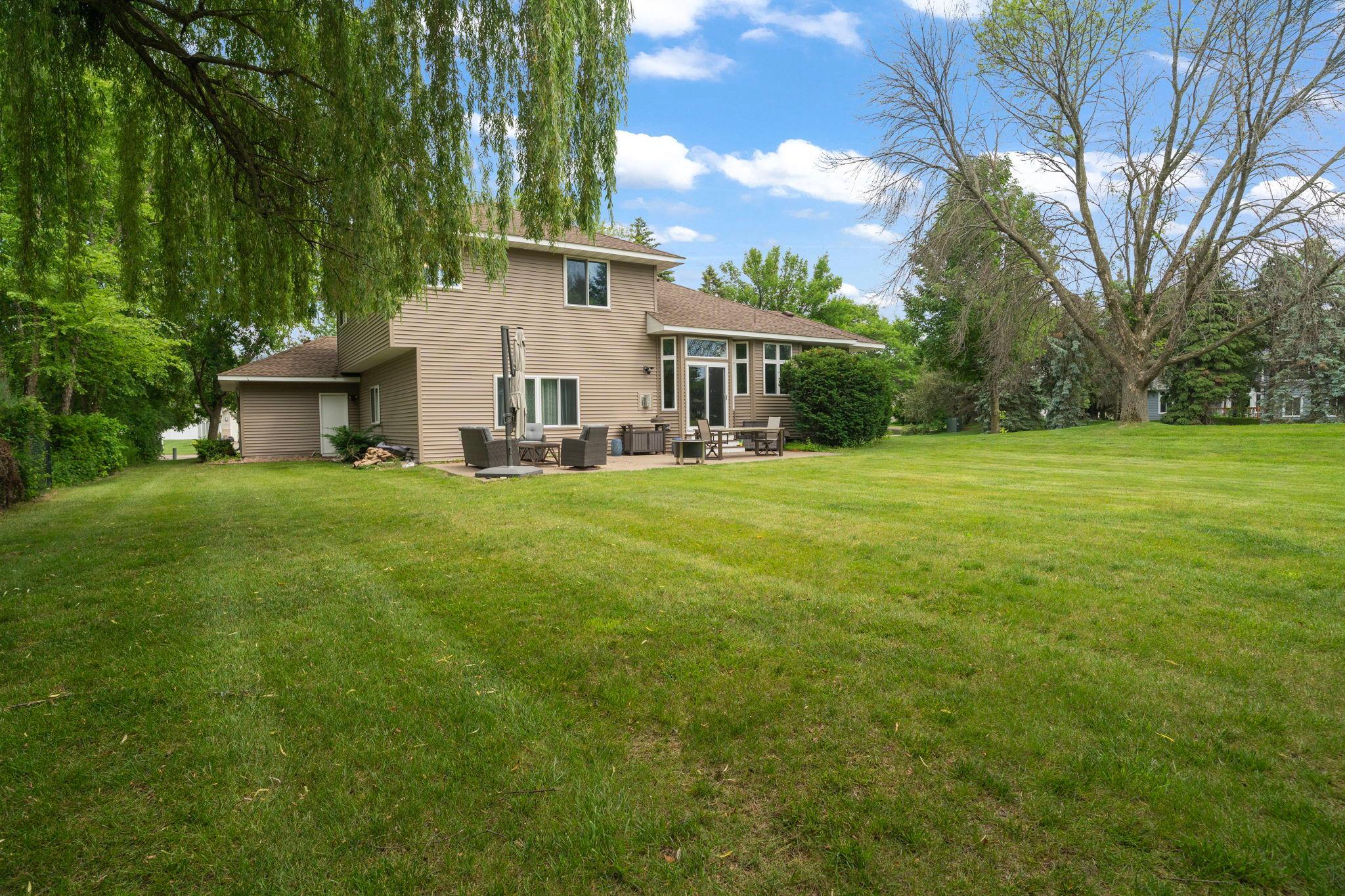 Willow branches drape gracefully over this stone patio, the wide backyard opening toward mature trees for privacy that's hard to find so close to town.