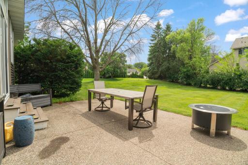 Patio seating overlooks a gently sloped, private lawn bordered by evergreens, the kind of backyard that feels a world away from the everyday.