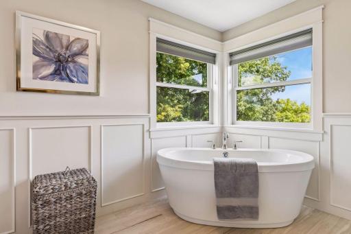 Freestanding soaking tub with treetop views.