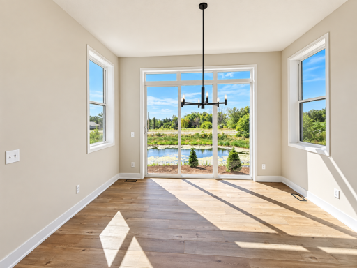 Light-filled dining area surrounded by windows and featuring a contemporary chandelier with beautiful views of the pond and surrounding landscape.