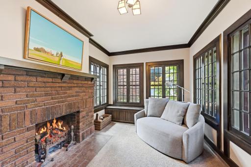 The cozy sunroom has a wood burning fireplace and large windows letting in plenty of light.