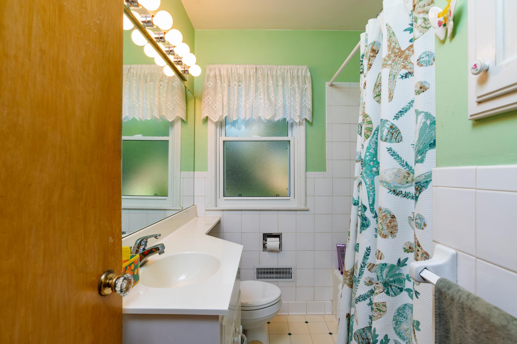 The main floor full bath with tub/shower combo and tile flooring and walls.