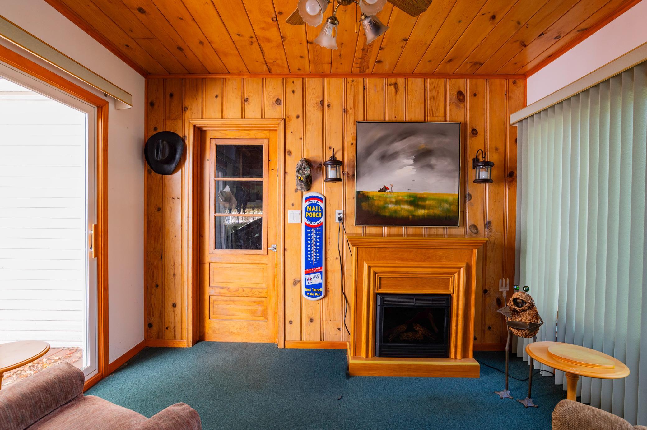Three season porch with access to garage, patio door to large deck and large west facing windows. Electric fireplace is excluded from the sale of the home.