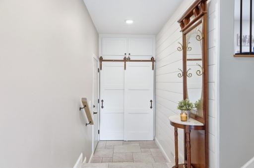 Bright inviting tiled foyer with barn door storage space.jpg