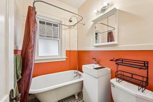 Main-level bathroom with tub, vanity, and natural light