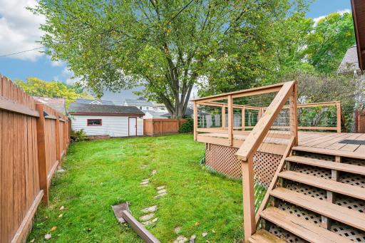 Backyard with deck, lawn, mature tree, and detached garage