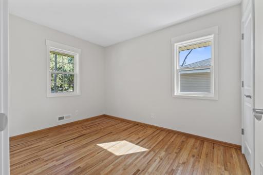 Two large new windows and fresh, light finishes make this bedroom feel especially bright and airy, while the refinished hardwood floors add warmth and character