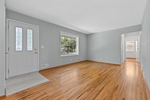 Step inside to a bright and inviting living room with beautifully refinished hardwood floors, fresh paint, new LVT entryway and abundant natural light through the large new windows.