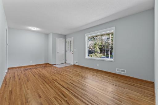Warm refinished hardwood floors and a large new window make the main living room feel bright and welcoming.