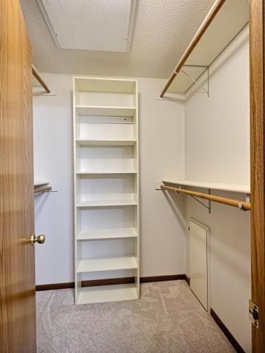 Walk in closet with shelving system and plenty of space for hanging clothes.