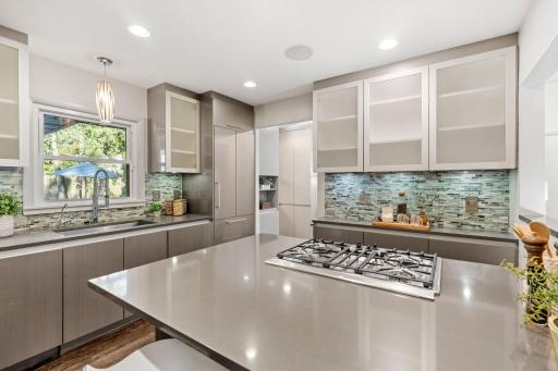 Paneled Refrigerator and Center Island with Cooktop and Downdraft