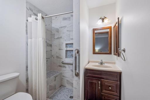 The beautifully remodeled primary bathroom features a newly completed walk-in shower with bench