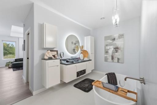 Free-standing, deep soaking tub with wall-mounted faucet, heated tile floors, custom cement sink & vanity countertop, backlit makeup mirror, modern storage cabinetry, pocket door with full-mirror.